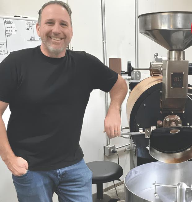 Greg Berkowitz standing beside the drum roaster at his roastery in Concord, California